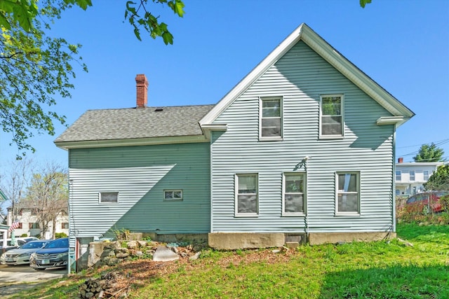 rear view of house with a chimney and a yard