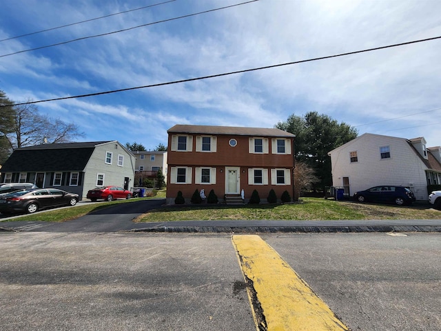 colonial house featuring uncovered parking and a front yard