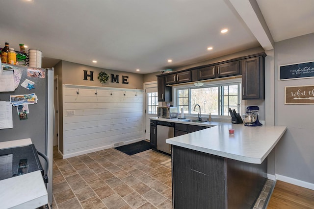 kitchen featuring black range with electric cooktop, a peninsula, light countertops, a sink, and dishwasher