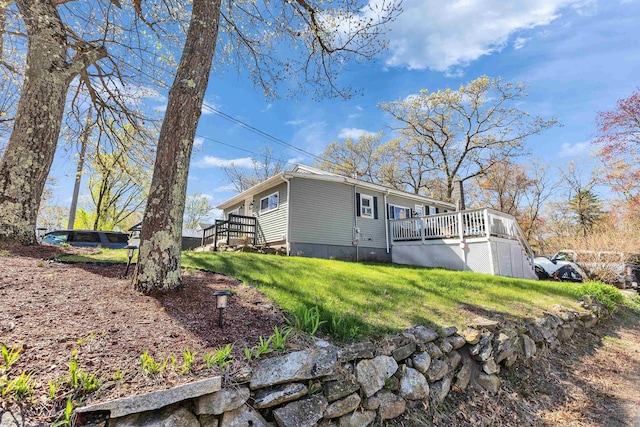 rear view of house featuring a wooden deck and a yard