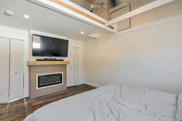 bedroom featuring recessed lighting, baseboards, a glass covered fireplace, and wood finished floors