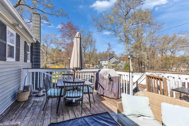 wooden deck with outdoor dining area and grilling area