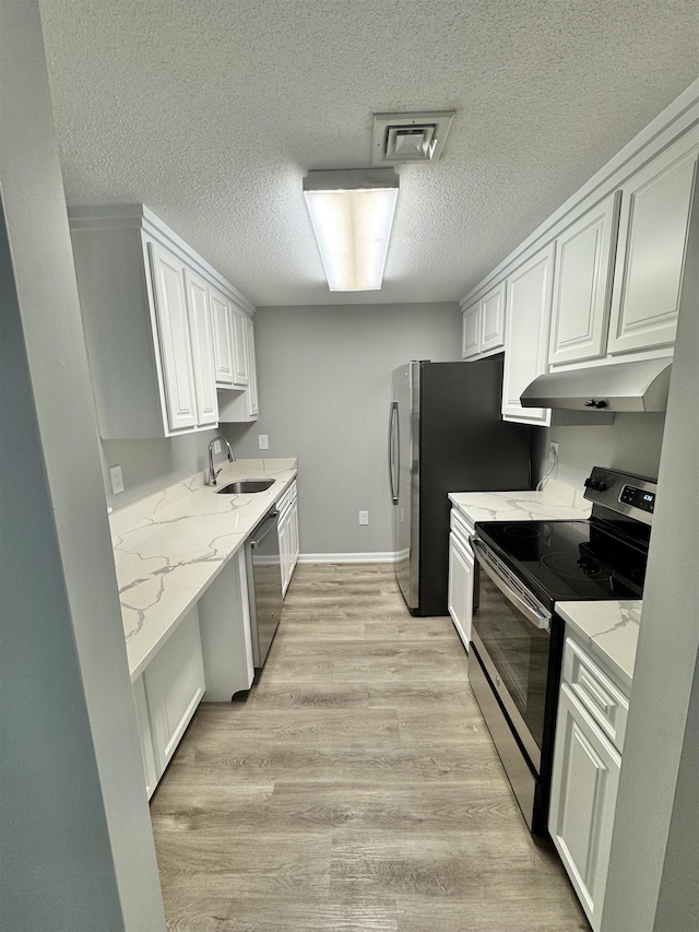 kitchen featuring a textured ceiling, visible vents, a sink, under cabinet range hood, and stainless steel appliances