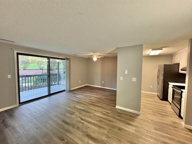 interior space with light wood-style floors, a ceiling fan, a textured ceiling, and appliances with stainless steel finishes