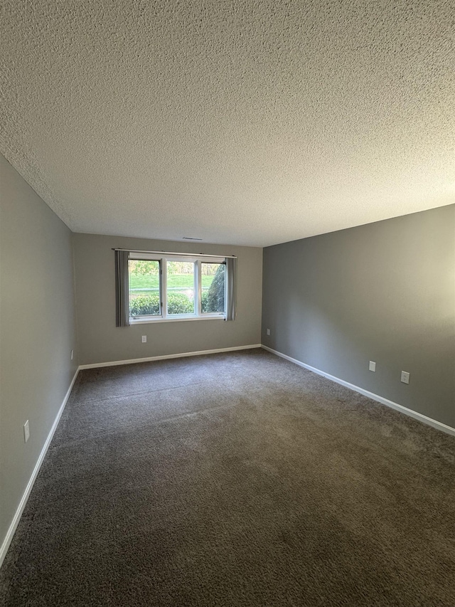 unfurnished room with dark carpet, a textured ceiling, and baseboards