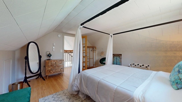 bedroom featuring wood finished floors and lofted ceiling