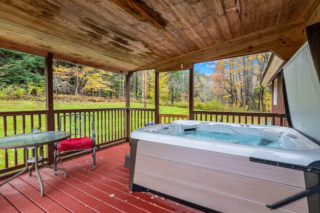 deck featuring a hot tub and a lawn