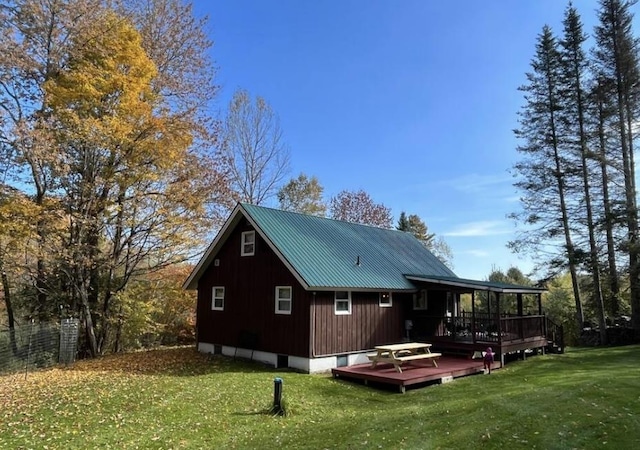 rear view of property featuring a lawn, a deck, and metal roof
