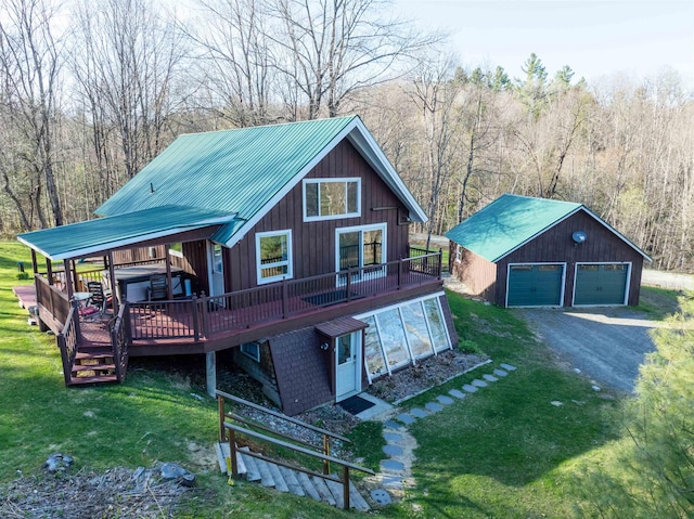 chalet / cabin with a garage, a wooden deck, an outdoor structure, and a front lawn