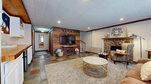living area featuring crown molding, baseboards, a fireplace, and stone tile flooring