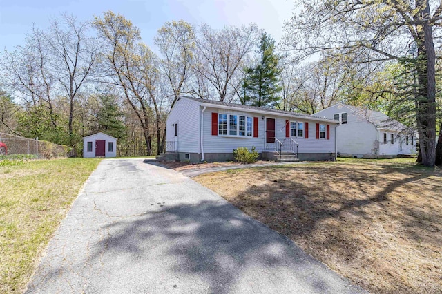 manufactured / mobile home with a storage shed, aphalt driveway, fence, and an outbuilding