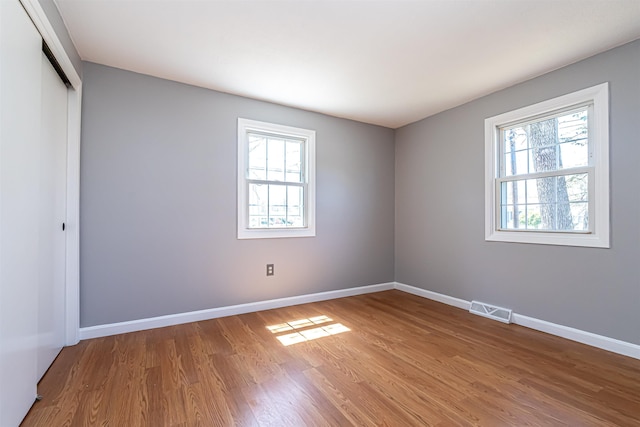 empty room featuring baseboards, visible vents, and wood finished floors