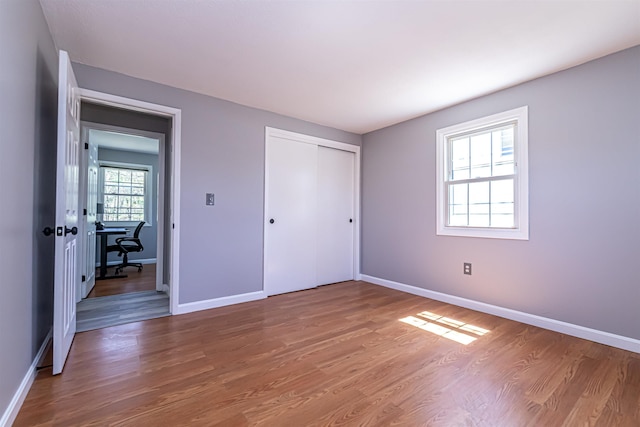 unfurnished bedroom with baseboards, wood finished floors, and a closet