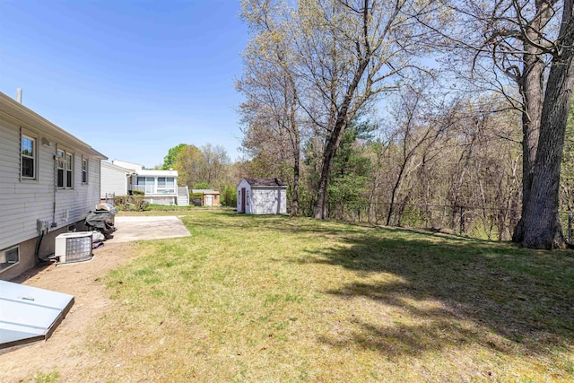 view of yard featuring fence, a storage shed, an outbuilding, cooling unit, and a patio area
