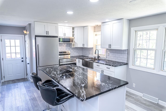 kitchen featuring visible vents, open shelves, a sink, white cabinets, and stainless steel appliances