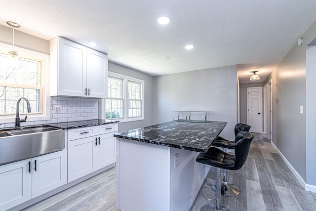 kitchen featuring light wood-style floors, a center island, dark stone countertops, and a textured ceiling