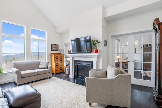 living room featuring high vaulted ceiling, dark wood finished floors, a glass covered fireplace, and french doors