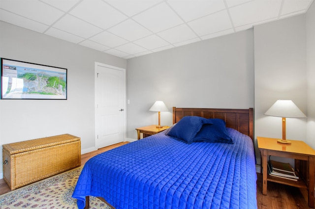 bedroom featuring a drop ceiling and wood finished floors