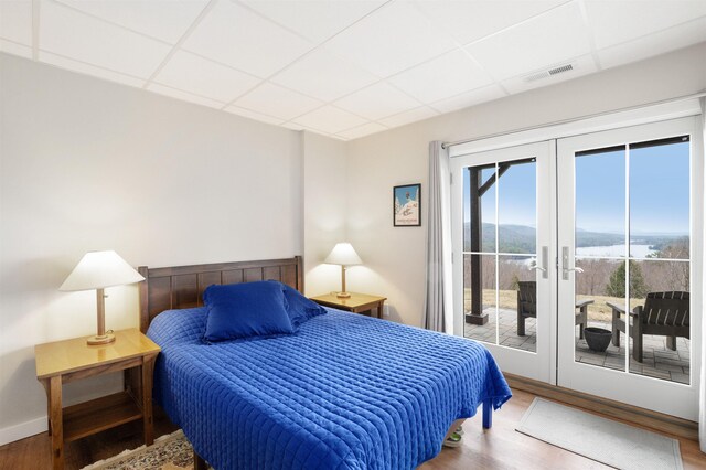 bedroom featuring french doors, a paneled ceiling, wood finished floors, and access to exterior