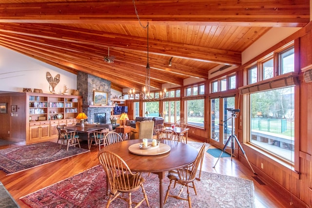 dining space with wood finished floors, wooden ceiling, vaulted ceiling with beams, and a fireplace