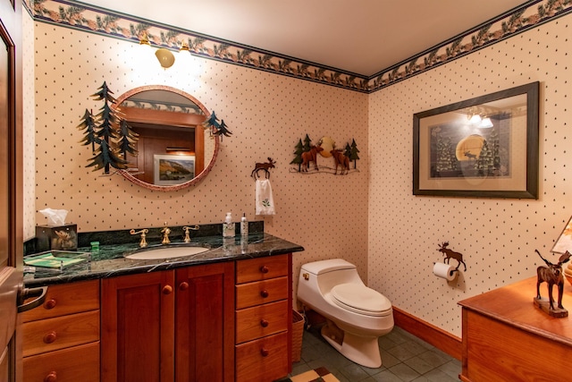 bathroom with tile patterned flooring, vanity, toilet, wallpapered walls, and baseboards