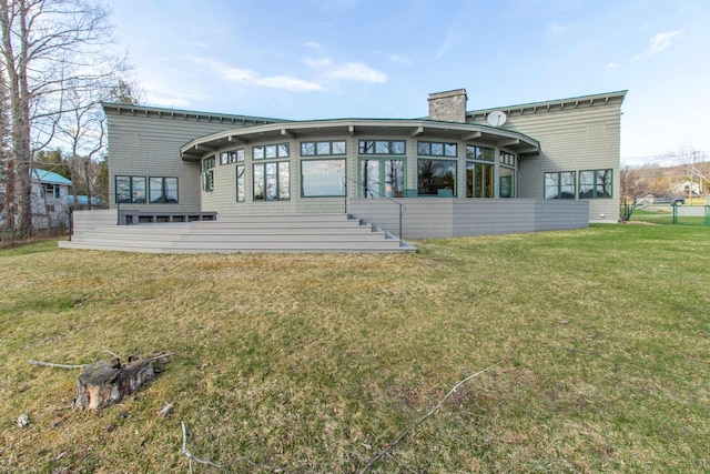 back of house with a lawn, a sunroom, and a chimney