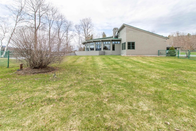 rear view of property with fence, a chimney, and a yard