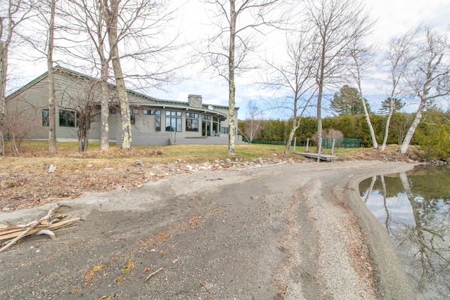 view of front of property with dirt driveway and a chimney