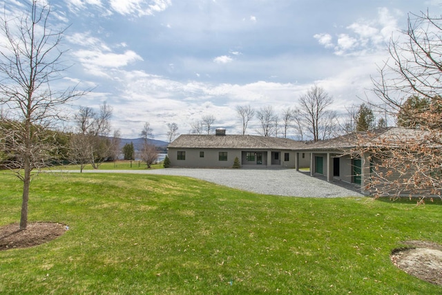 rear view of house featuring a yard, a chimney, and a patio area