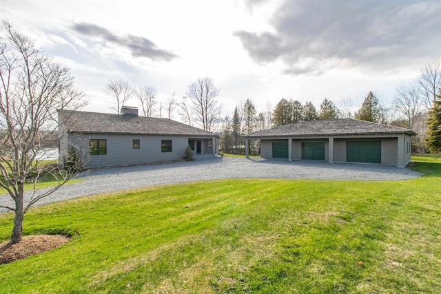 back of house with a garage, an outbuilding, a chimney, and a yard