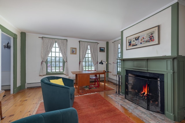 living area featuring a fireplace with flush hearth, light wood-style floors, crown molding, and baseboard heating