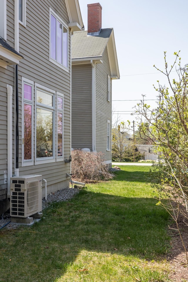 view of property exterior with a lawn, ac unit, a chimney, and entry steps