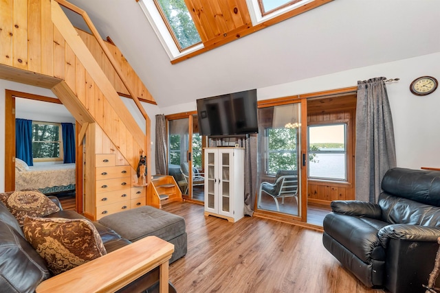 living area with wood finished floors, a healthy amount of sunlight, and high vaulted ceiling