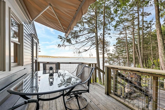 deck with a water view and outdoor dining area