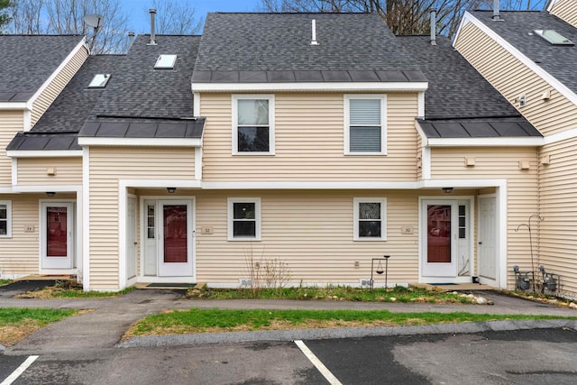 townhome / multi-family property featuring a standing seam roof, a shingled roof, uncovered parking, and metal roof