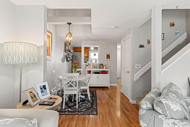 dining area featuring baseboards, light wood finished floors, a chandelier, and stairs