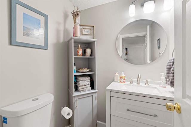 half bath with vanity, a textured ceiling, and toilet