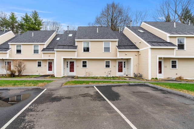 townhome / multi-family property featuring a standing seam roof, roof with shingles, uncovered parking, and metal roof