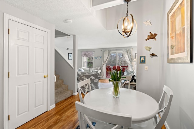 dining area with stairs, baseboards, a chandelier, and light wood finished floors