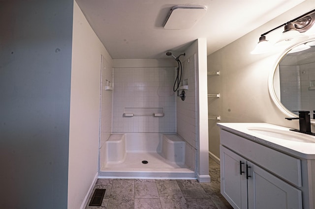 bathroom featuring vanity, baseboards, walk in shower, and visible vents