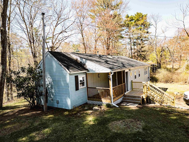 rear view of house featuring a lawn, a shingled roof, and a porch