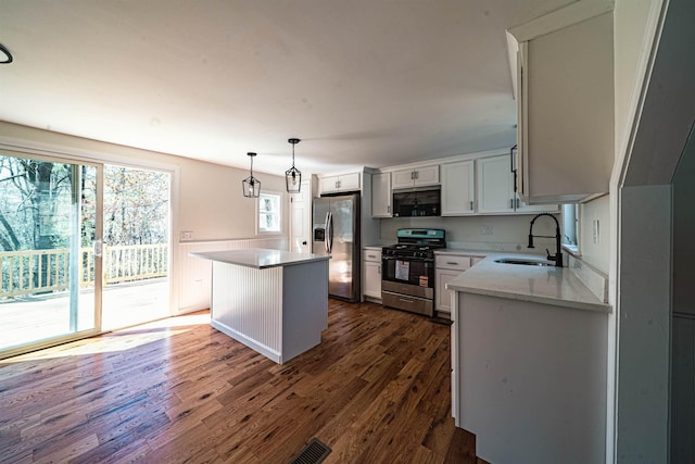 kitchen with pendant lighting, a center island, a sink, dark wood-style floors, and stainless steel appliances