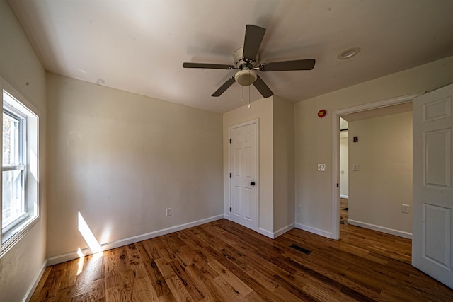unfurnished bedroom with baseboards, visible vents, multiple windows, and wood finished floors