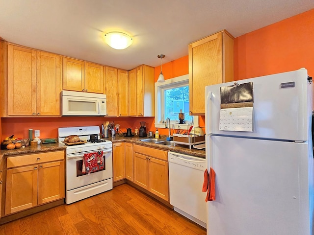 kitchen with dark countertops, white appliances, light wood-style floors, a sink, and decorative light fixtures