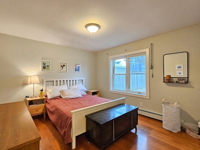 bedroom with wood finished floors and a baseboard radiator