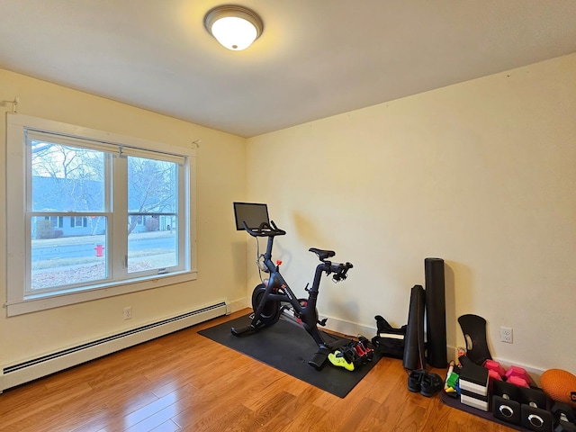 exercise area with wood finished floors and baseboard heating