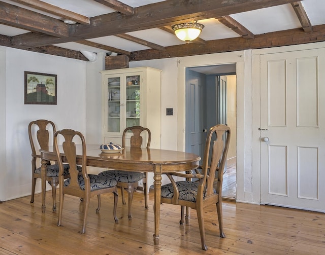 dining room featuring beamed ceiling, baseboards, and light wood finished floors