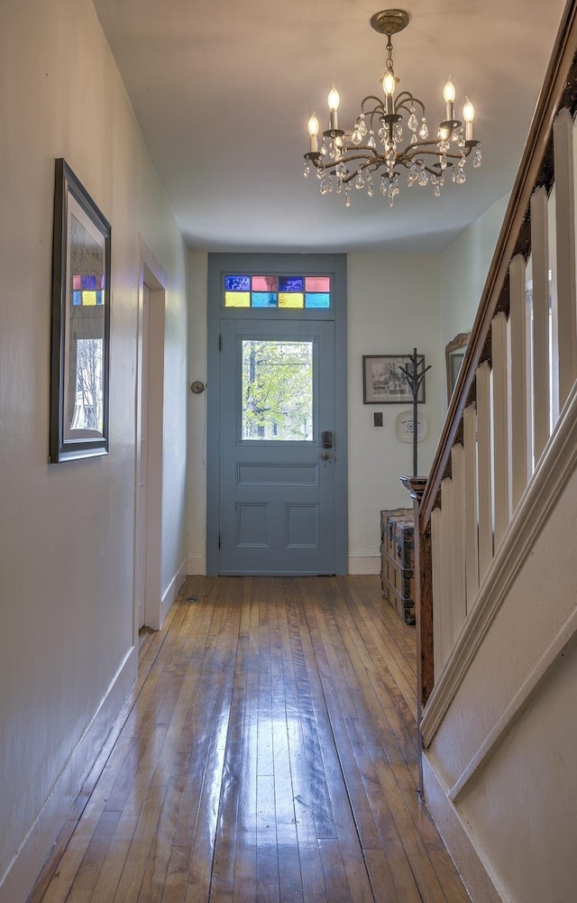 foyer entrance featuring stairway, an inviting chandelier, baseboards, and hardwood / wood-style flooring