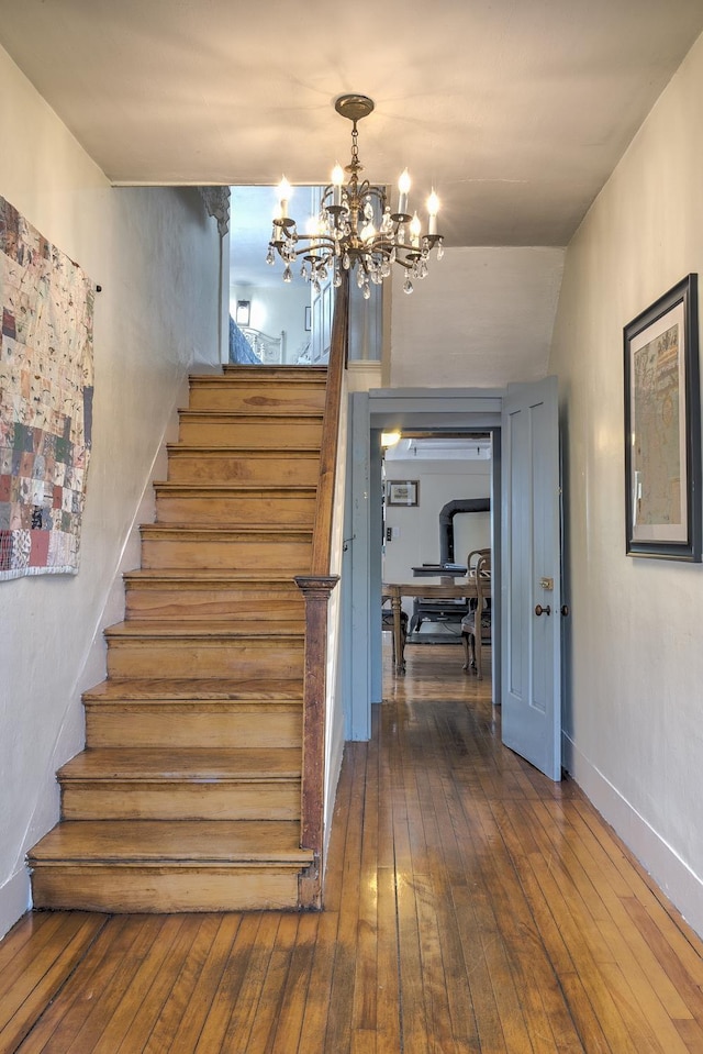 stairs with wood-type flooring and a notable chandelier