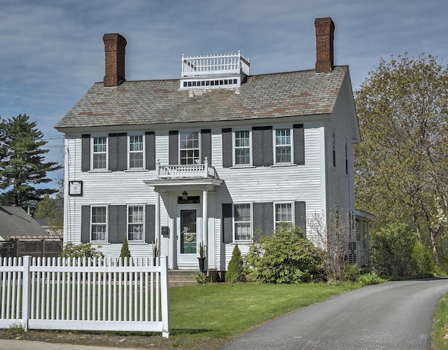view of front of home featuring a high end roof, fence, a chimney, and a front yard